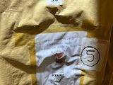 a yellow shirt with a tag on it sitting on a table