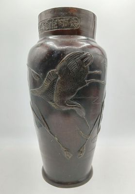 a brown vase with a bird on it on a white surface