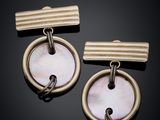 a pair of gold and mother of pearl earrings on a black background