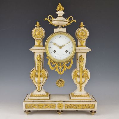 une horloge blanche et dorée posée sur un socle, sur fond gris