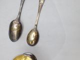 several spoons and spoon rest on a white surface with a gold lid