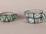 pair of green and white coffee cups sitting on top of a table