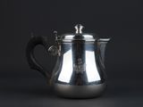 an antique silver coffee pot on a black background