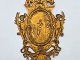 une plaque en or richement décorée, représentant des anges et une croix, accrochée au mur