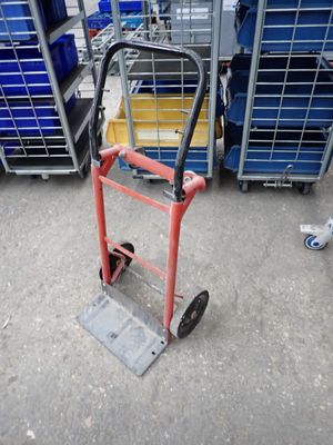un diable rouge muni d'une poignée métallique dans un entrepôt