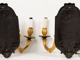 pair of black and gold sconces mounted on a wall