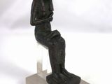 statue représentant un homme assis sur un tabouret, les mains posées sur les genoux