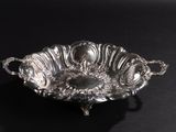 an antique silver plate with handles and handles on a black surface