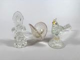 trois figurines en verre posées sur une surface blanche