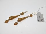 une paire de boucles d'oreilles en or ornées de feuilles, avec des feuilles qui pendent