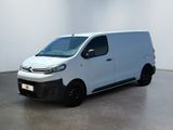La camionnette blanche est garée dans une grande pièce aux murs blancs.