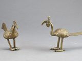 brass figurines of a bird and a flamingo on a gray background