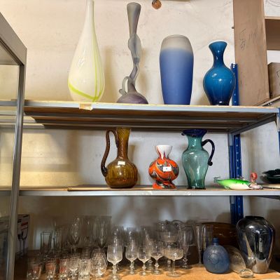 de nombreux vases et verres posés sur une étagère dans une pièce