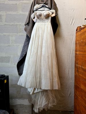 a white dress hanging on a wall next to a dresser