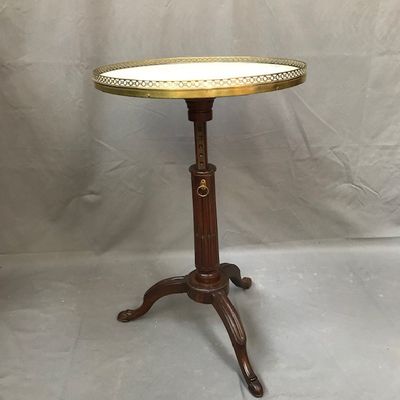 an antique brass plate topped table on a wooden stand