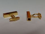 two pairs of gold cufflinks on a white surface