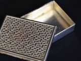 a silver box with a pattern on it on a black surface