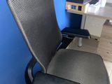 a black office chair sitting in front of a blue wall