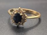 Gros plan sur une bague en or sertie d'une pierre bleue entourée de diamants blancs