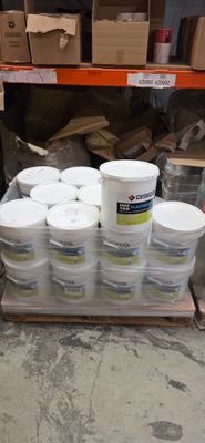 Plusieurs seaux de peinture sont empilés sur une palette dans un entrepôt