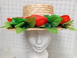 un chapeau de paille orné de roses rouges et de feuilles vertes sur la tête