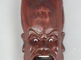une image représentant un masque en bois accroché au mur, avec une expression surprise