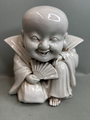 une petite figurine représentant un enfant souriant tenant un éventail