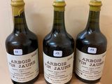 three bottles of wine sit on a wooden shelf in front of a wall