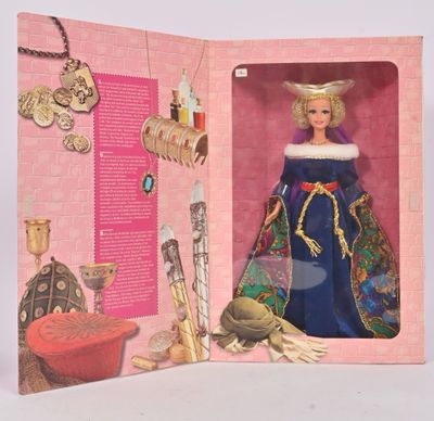 une poupée dans une boîte rose sur laquelle figure l'image d'une femme vêtue d'une robe bleue et portant des bijoux en or