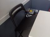 a white table with a black chair next to it