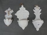 Trois vases blancs sont suspendus au mur à l'aide d'une corde.