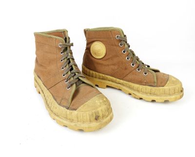 une paire de bottes marron posées sur une surface blanche, sur fond blanc