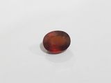 an oval shaped red garnet stone on a white surface