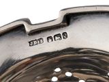 a close up of a metal strainer on a white surface