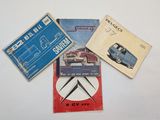 trois livres posés sur une table blanche, avec une voiture bleue et un camion rouge