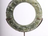 a green stone ring on a stand on a white background