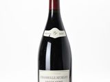 the bottle of red wine is sitting on a white surface