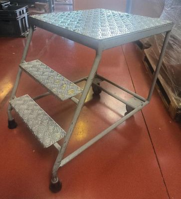 une table en métal sur laquelle se trouvent deux marches, dans une pièce