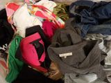 a pile of clothes on a bed with a cell phone in it