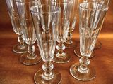 six empty wine glasses are lined up on a brown surface