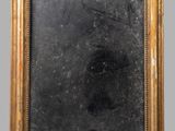 an old gold framed mirror with a black background on a gray wall