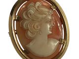 Une broche de couleur dorée représente le profil d'une femme.