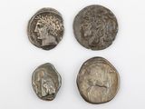 trois pièces romaines, dont l'une représente une tête et l'autre un visage