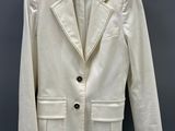 the white jacket is hanging on a hanger on a gray wall