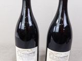 two bottles of wine sitting on top of a table next to each other