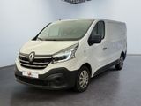 La camionnette blanche est garée dans une grande pièce au sol noir.