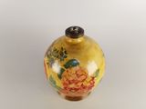 a yellow vase with flowers on it on a white surface