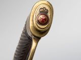 a close up of a sword with a red stone in the center