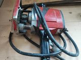 une photo d'une perceuse électrique rouge et noire posée sur un plancher en bois