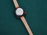 a close up of a watch sitting on top of a green surface